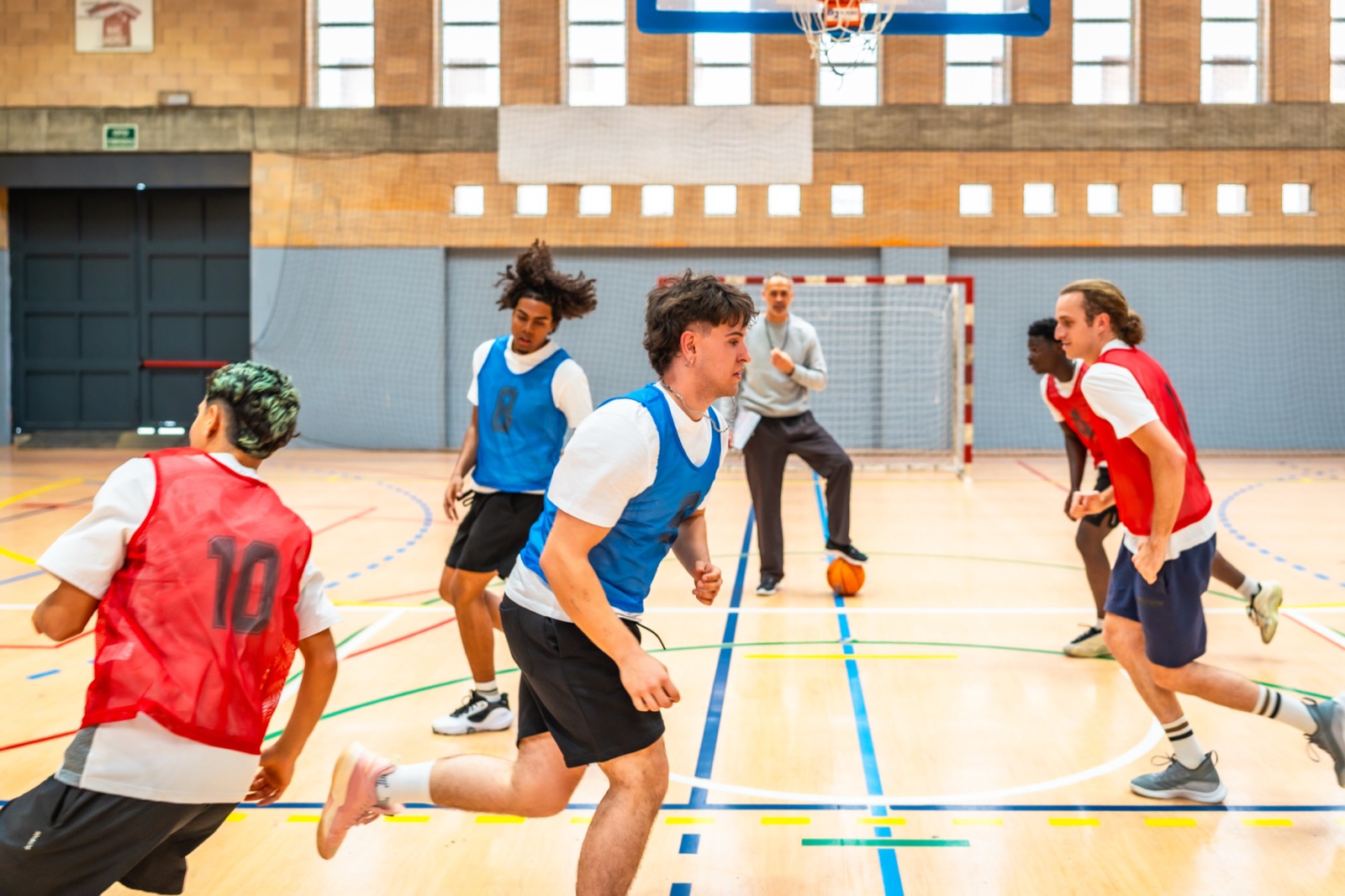 Teenage and college-age athletes scrimmaging during a gym basketball training session